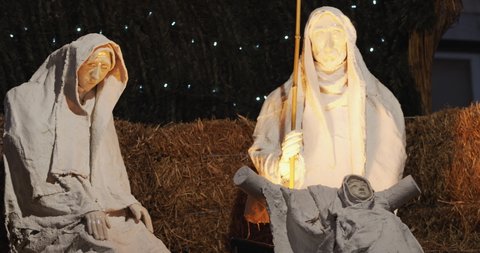Jesus Nativity Scene with decorated Christmas lights and garland in the middle of a street. Slow motion.