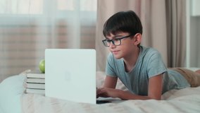Using ChatGPT.Chat GPT.Artificial Intelligence.Home Isolation, Online Learning, Remote Work, New Education. A boy during online learning lies on the bed at home