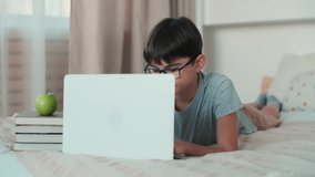 Using ChatGPT.Chat GPT.Artificial Intelligence.Home Isolation, Online Learning, Remote Work, New Education. A schoolboy during online learning lies on a bed at home