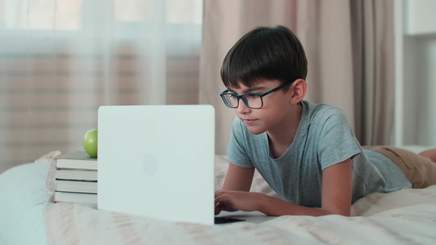 Home Isolation, Online Learning, Remote Work, New Education. A schoolboy during online learning lies on a bed at home Royalty-Free Stock Footage #1063188793