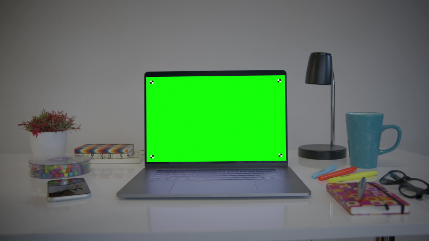 Laptop Computer Showing Green Chroma Key Screen. Colorful desk elements. Dolly in. Home office. Track points with perspective corner pin.    Royalty-Free Stock Footage #1063190662