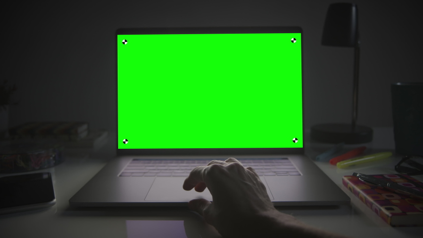 Laptop with green screen. Female hands typing and scrolling on a track pad. Dark office. Dolly in. Perfect to put your own image or video. Track points with perspective corner pin.   Royalty-Free Stock Footage #1063190668