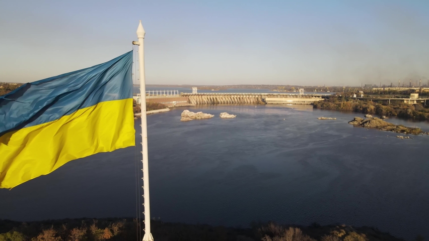 Zaporozhye, Ukraine, dam, aerial view of the Dnieper hydroelectric station. Flag of Ukraine, the flag is evolving. Royalty-Free Stock Footage #1063192183