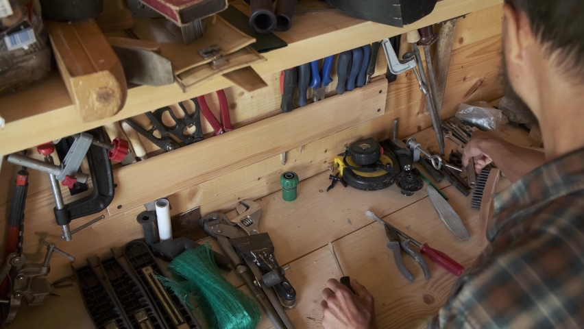 Top view bearded man joiner woodworker choosing construction carpentry tools in his workshop. DIY concept. | Shutterstock HD Video #1063193551