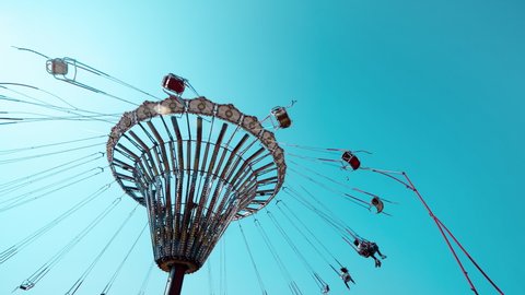 A rotating chair swing ride carousel with teenagers enjoying the ride in a parisian amusement park.