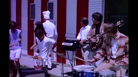 CIRCA 1967 - In this exploitation movie, a rock band performs outside a KFC and Colonel Sanders gives them free fried chicken.