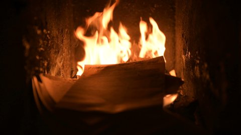 Blazing hot fire flame warming old fireplace burning wood logs, paper letters, documents, books manuscripts in dark dusk coal ash cinder