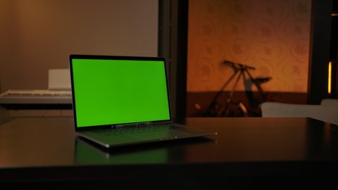 Zoom in view of modern laptop with chromakey screen placed on table in cozy workplace at home.
