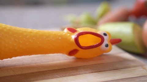 The head of silicone toy chicken with frightened face is cut off with cleaver, close up. Grotesque message of vegetarians about refusing to eat meat and kill animals.
