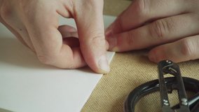Close-up of the master's hands make a neat and precise fold of paper for making patterns. Slow-motion video.