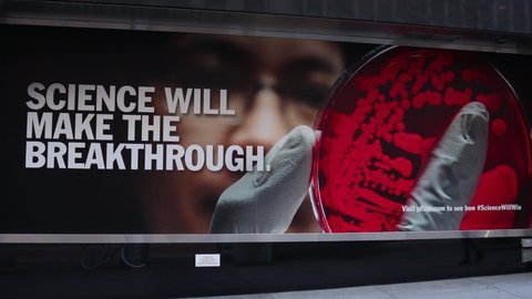 New York, New York USA - November 29 2020: Science Will Make The Breakthrough Sign outside the Pfizer World Headquarters Building in New York City with a Masked Woman Walking Past