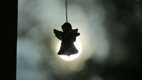 Angel hanging over blurry light. Christmas Eve decoration. 