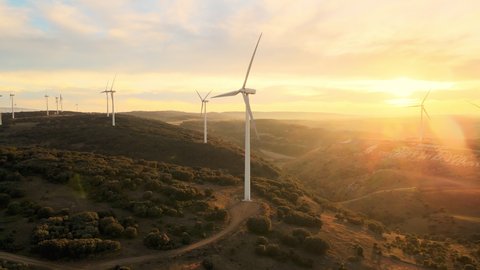 Amazing aerial view of wind turbines producing clean renewable energy, at a vibrant Sunset. High quality 4k footage