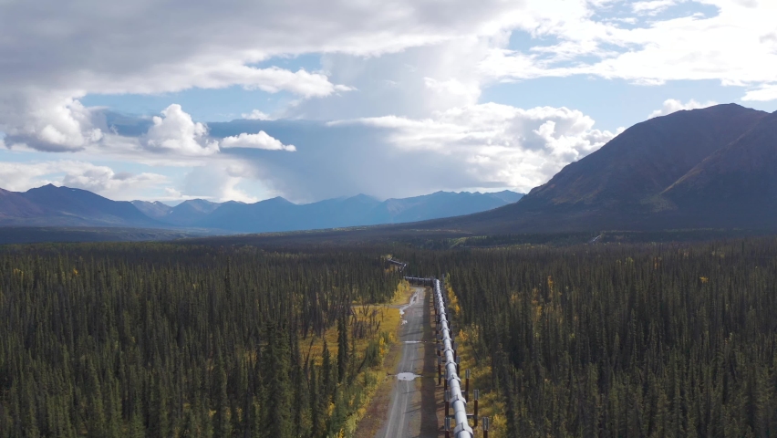 Drone follows high above trans-Alaska pipeline on September autumn day with fall colors and sun with distant mountains. Royalty-Free Stock Footage #1063214422