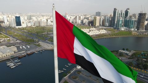 Top closeup view of the Flag of the United Arab Emirates waving in the air over Sharjah's Flag Island, The national symbol of United Arab Emirates, UAE National Day, 4K Video