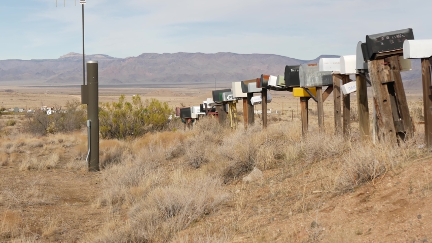 Row of vintage drop boxes on road intersection, arid Arisona desert, USA. Postal retro mailboxes on roadside of tourist Route 66. Address on old-fashioned nostalgic metal grunge postbox on pillar.