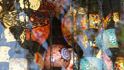 Colourful turkish lamps from glass mosaic glowing. Arabic multi colored authentic retro style lights. Many illuminated moroccan craft lanterns. Oriental islamic middle eastern decor. Shiny folk shop.