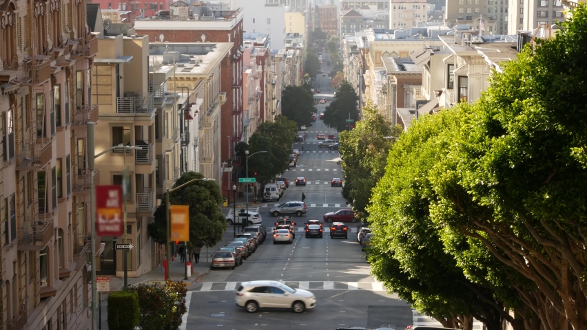 Iconic hilly street and crossroads in San Francisco, Northern California, USA. Steep downhill road and pedestrian walkway. Downtown real estate, victorian townhouses abd other residential buildings. Royalty-Free Stock Footage #1063219927