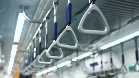 Hanging alley of public transportation, bus or train interior. Medium shot of handles hanging on moving train