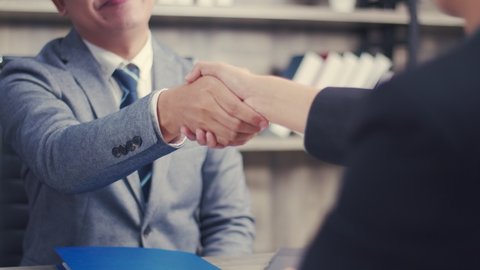 Asian businessman shaking hands partnership deal business while standing indoors in the office, Happy confident accept handshaking employer getting hired at a new job.