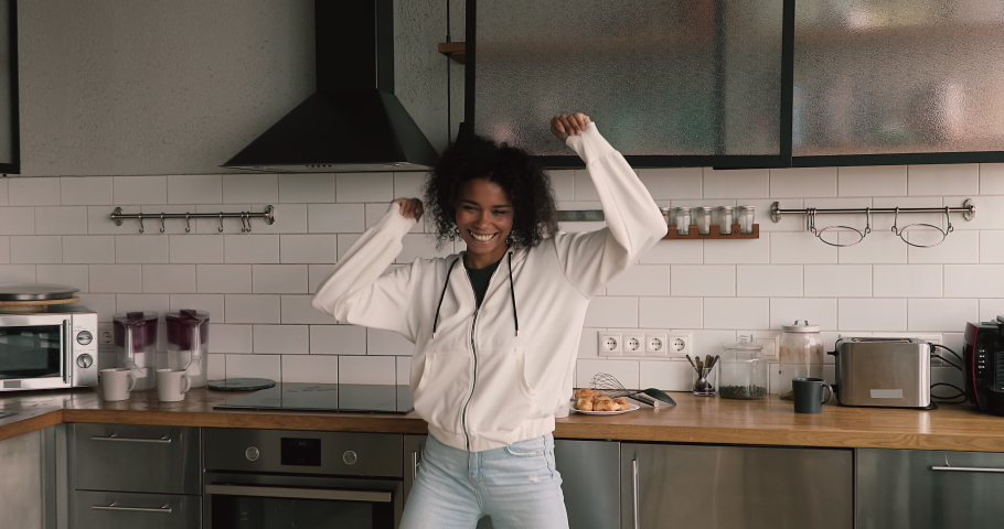 Happy beautiful african woman dancing to energetic music in modern kitchen, celebrating freedom in own apartment, have fun enjoy free leisure weekend carefree time indoor. No stress, new home concept | Shutterstock HD Video #1063225519