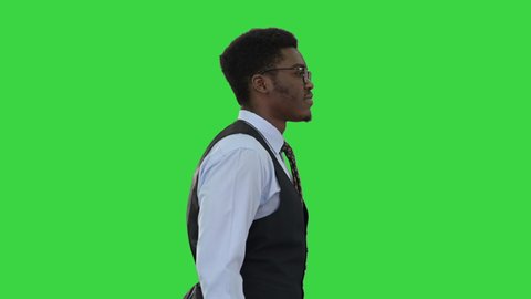Young African American business man in glasses walking confidently on a Green Screen, Chroma Key.