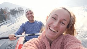 Taking a selfie on a canoe. Young people canoeing on a beautiful lake taking cool video selfies. Couple having a video conversation. POV