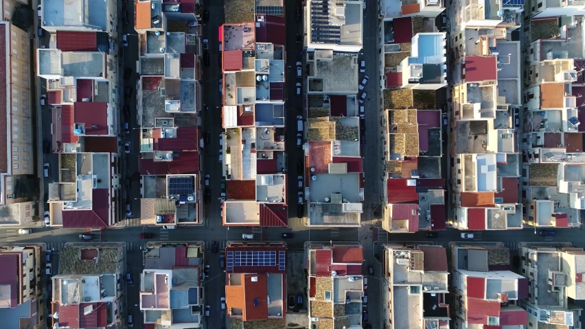 Aerial top down view of city building block located in metropolitan town flight over roofs and streets with vehicles driving around filmed by drone moving up slowly showing more of urban environment Royalty-Free Stock Footage #1063230391