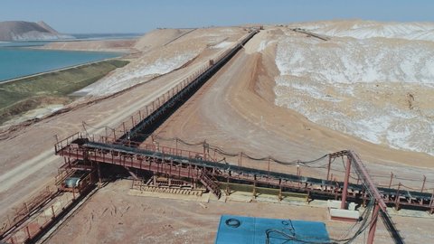 Mining of potash salt, aerial view of salt piles and industrial quarries, conveyor line working process, view from height of hills of sand, sludge and mining waste.