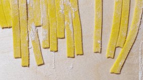 Tagliatelle pasta in flat lay.Traditional Italian noodles filmed directly from above on wooden table in restaurant kitchen.4K ultra hd video clip 