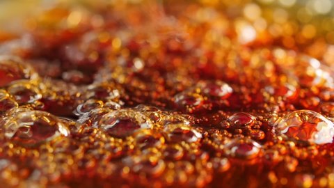 Macro bubbles of boiling caramel. Shallow depth of field, low angle. Slow motion.