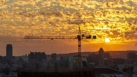 Cranes in the foreground and colorful altocumulus clouds in the background in sunset time. Beautiful city landscape at dusk. A concept of economic development.