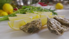Oysters with lemon closeup. Fresh Oyster on half shell on big plate in restaurant. Served table. 4K UHD video slow motion.