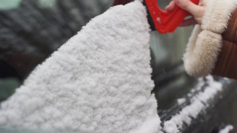 The girl wipes the side window on the driver's side of the first snow as it fell at night. A red triangular paddle with rubber pulls wet snow.