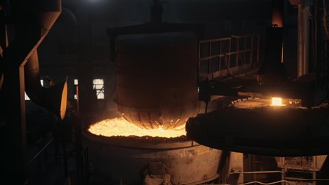 Steel Making Plant. Crane Transported Tank With Scrap Metal and Dropped to the Huge Vessel for Melting Metal, Metal Casting Production line. Industrial oven. Heavy industry. Metallurgy. Slow Motion