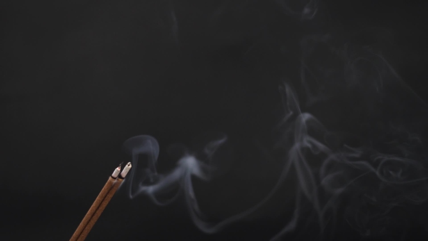 Slow motion shot of Incense Stick emitting smoke against the black background | Shutterstock HD Video #1063243540
