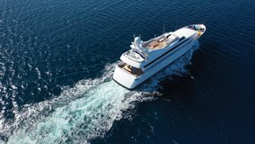 Aerial drone tracking video of luxury yacht cruising in deep blue open ocean sea