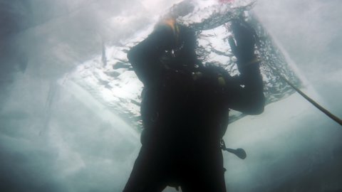 Researcher traveler diver underwater under ice on bottom of Lake Baikal in Siberia Of Russia.
