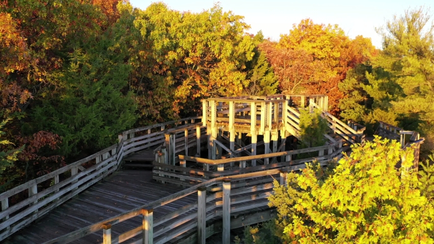 Panning aerial shot of the boardwalks of Eagles Cliff Overlook during the Autumn season with the leaves changing colors.