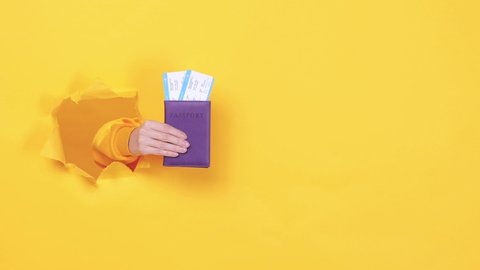 Close up traveler tourist man woman hands hold plane passport ticket isolated through torn yellow background studio. Passenger traveling abroad on summer weekends getaway. Air flight journey concept.