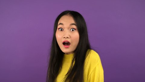 three-quarter portrait of young surprised joyful asian woman. isolated purple background. 4K