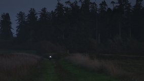 Motorcycle rider approaching on rural path at night . Coupeville, Washington, United States