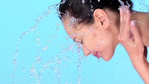 Woman washing her clean face with water. Young adult girl is  washing face with water. Slow motion.  Skin care. Healthy skin concept. 
