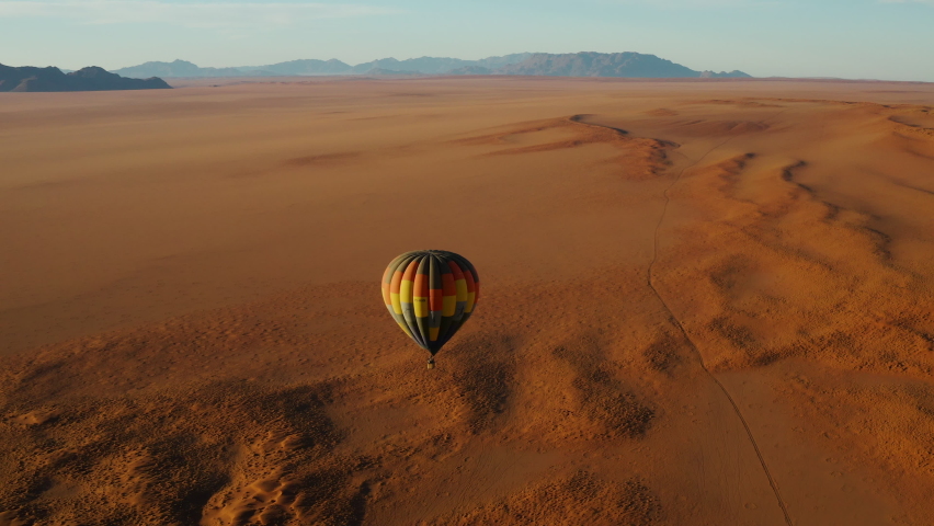 Breathtaking scenic aerial view of a hot air balloon flying over the endless sand dunes of the Namib desert, Namibia Royalty-Free Stock Footage #1063264858