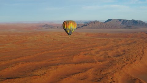 Breathtaking scenic aerial view of a hot air balloon flying over the endless sand dunes of the Namib desert, Namibia