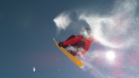 SLOW MOTION TIME WARP, LENS FLARE, BOTTOM UP: Fearless snowboarder does a spin trick while riding off a big air kicker. Snowflakes sparkle in the sunshine as male tourist does snowboarding tricks.