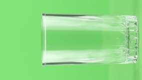 Vertical video Milk pouring into glass close up isolated on light green background . Milk is holesome and natural product for healthy lifestyle