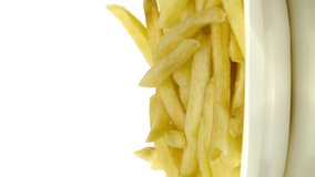 Vertical video Golden french fries on plastic disposable plate rotating on isolated white background. Fast food concept, unhealthy junk food, tasty yummy fried potatoes. Copy text space