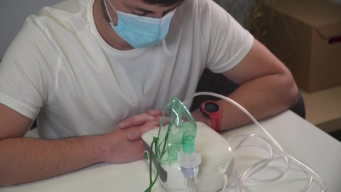Man makes inhalation using nebulizer at home. Male treated independently with inhaler with, spray medicine for upper and lower respiratory tract. Treating allergies, asthma, pneumonia with nebulizer.