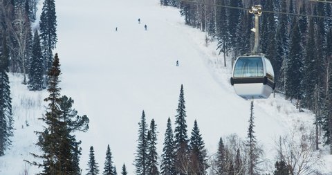 Lift cabins in a mountain ski resort. The movement of ski lifts in a snowy winter mountain.  Russia.